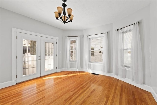 entryway with french doors, an inviting chandelier, and light hardwood / wood-style floors