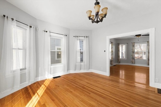 unfurnished room with hardwood / wood-style floors, a chandelier, and a healthy amount of sunlight