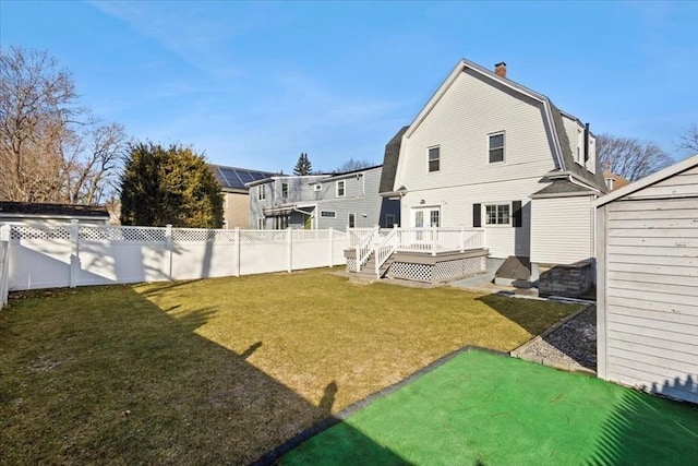 back of house with a deck and a lawn