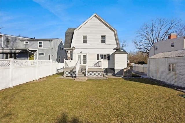 back of property with a deck and a lawn