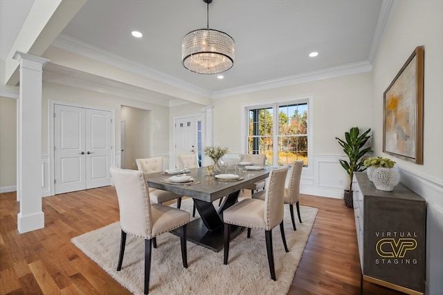 dining space featuring ornate columns, crown molding, and light wood-type flooring