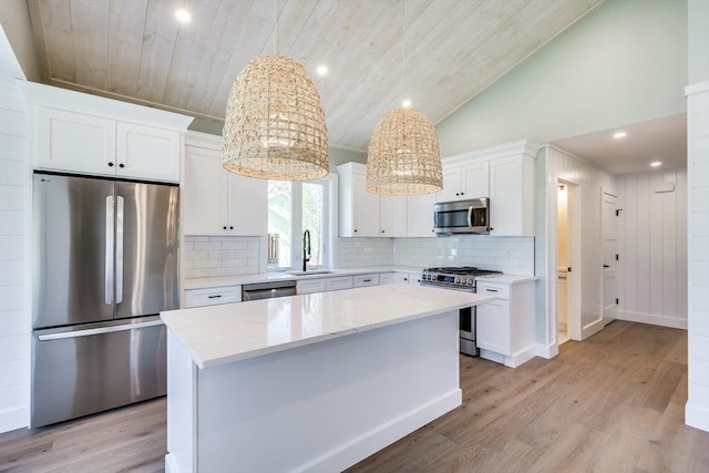 kitchen with appliances with stainless steel finishes, a kitchen island, white cabinetry, sink, and hanging light fixtures