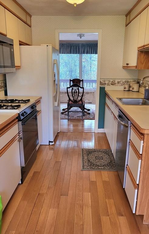 15 Iris Way Unit 27, Haverhill, MA 01830 - kitchen featuring wallpapered walls, appliances with stainless steel finishes, a sink, light wood-type flooring, and light countertops