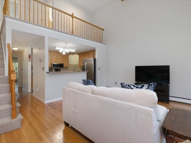 44 Casablanca Ct Unit 44, Haverhill, MA 01832 - living room featuring stairway, light wood-style floors, a baseboard radiator, a high ceiling, and baseboards