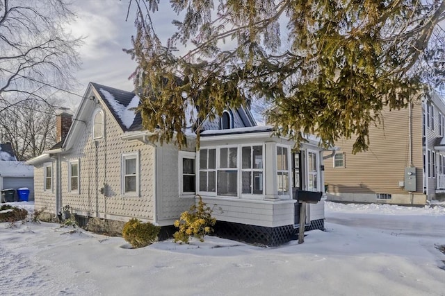 snow covered property with a sunroom and a chimney