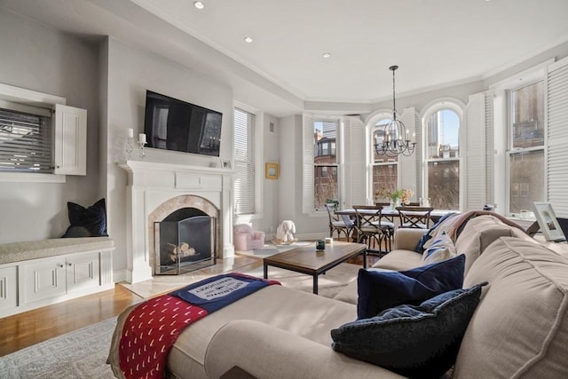 living room with crown molding, a notable chandelier, and light wood-type flooring