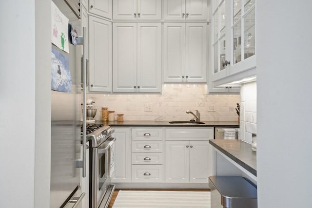 kitchen featuring sink, light hardwood / wood-style floors, decorative backsplash, white cabinets, and appliances with stainless steel finishes