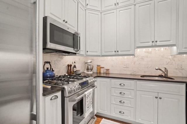 kitchen with white cabinetry, sink, stainless steel appliances, tasteful backsplash, and light wood-type flooring