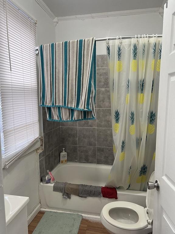 bathroom with shower / bath combo with shower curtain, hardwood / wood-style flooring, toilet, and ornamental molding