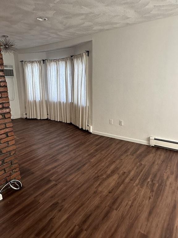 spare room featuring dark wood-type flooring, a textured ceiling, and baseboard heating