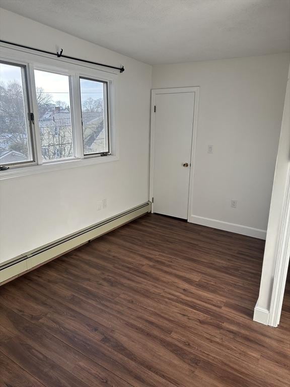 empty room with a baseboard heating unit and dark wood-type flooring