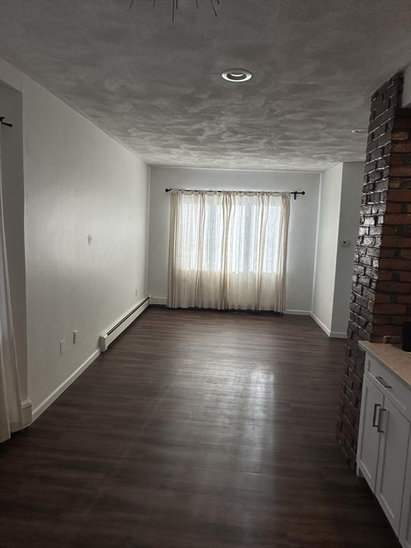 spare room with dark wood-type flooring and a baseboard radiator