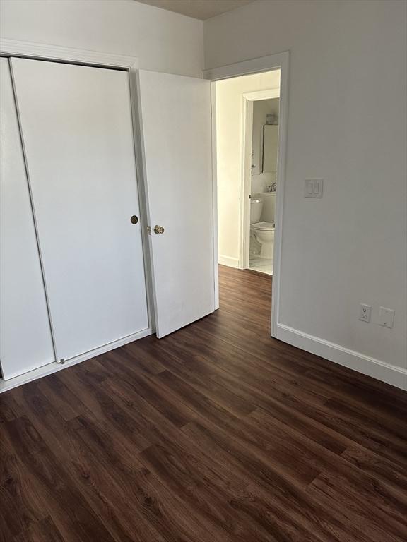 unfurnished bedroom featuring dark wood-type flooring and a closet