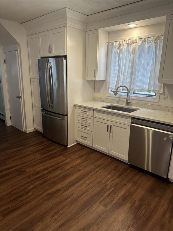 kitchen with dark wood-type flooring, sink, white cabinetry, light stone counters, and stainless steel appliances