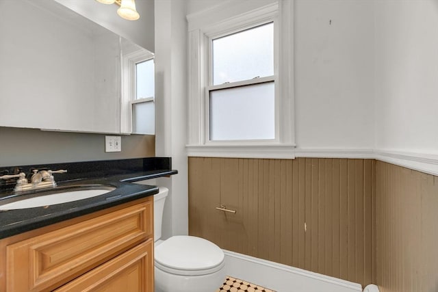 bathroom featuring vanity, toilet, and wood walls