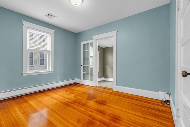 empty room with hardwood / wood-style floors and a baseboard heating unit