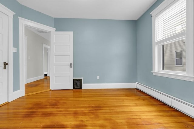 unfurnished bedroom featuring light wood-type flooring and baseboard heating