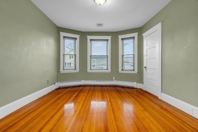 unfurnished room featuring baseboard heating and light wood-type flooring