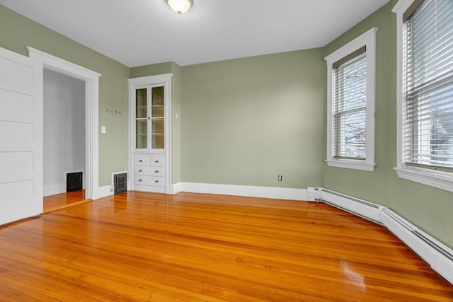 unfurnished bedroom with wood-type flooring and a baseboard radiator