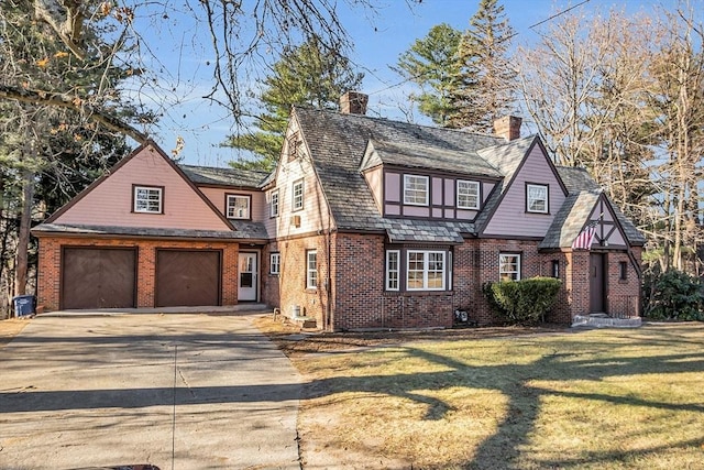 tudor home featuring a front yard and a garage