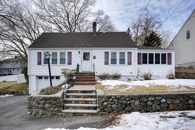 view of front of home featuring a garage, roof with shingles, and a chimney