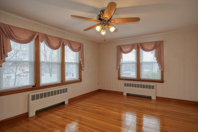 unfurnished room featuring radiator, wallpapered walls, and light wood-type flooring