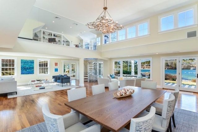 dining room with hardwood / wood-style flooring, a high ceiling, visible vents, french doors, and an inviting chandelier