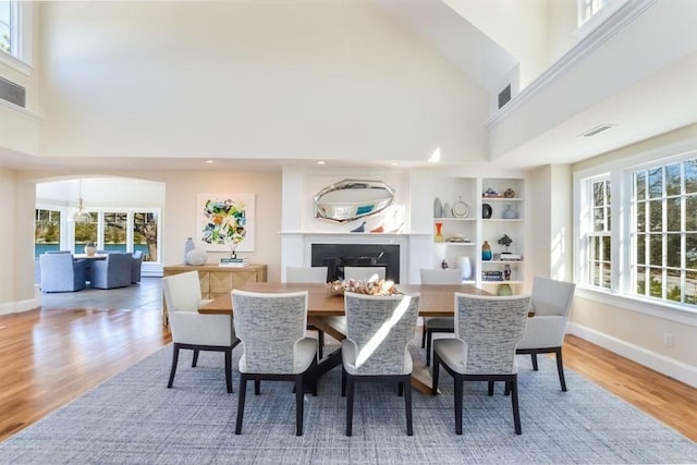 dining area featuring a glass covered fireplace, wood finished floors, visible vents, and a healthy amount of sunlight