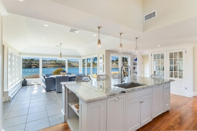 kitchen with a kitchen island with sink, visible vents, open shelves, and a sink