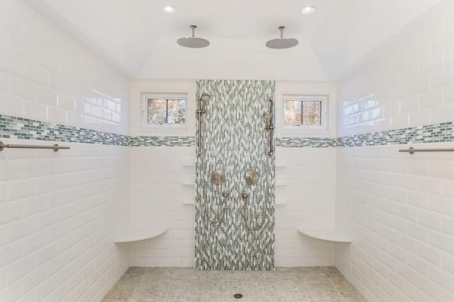 full bathroom with tile walls, a tile shower, and a wealth of natural light