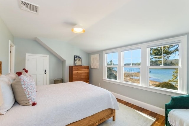 bedroom with wood finished floors, visible vents, vaulted ceiling, and multiple windows