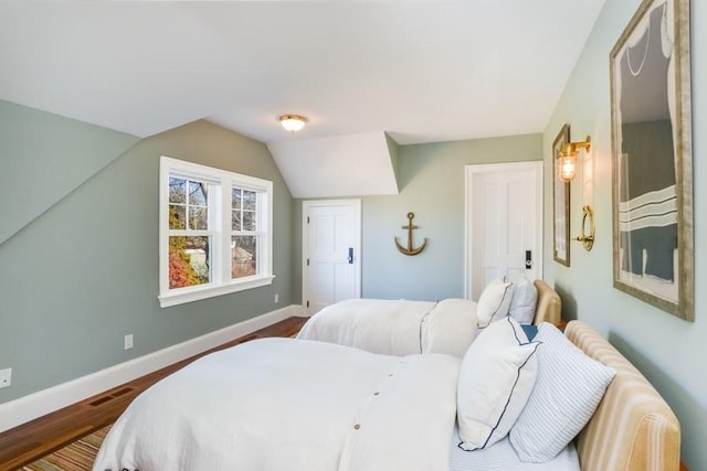 bedroom featuring lofted ceiling, visible vents, dark wood finished floors, and baseboards