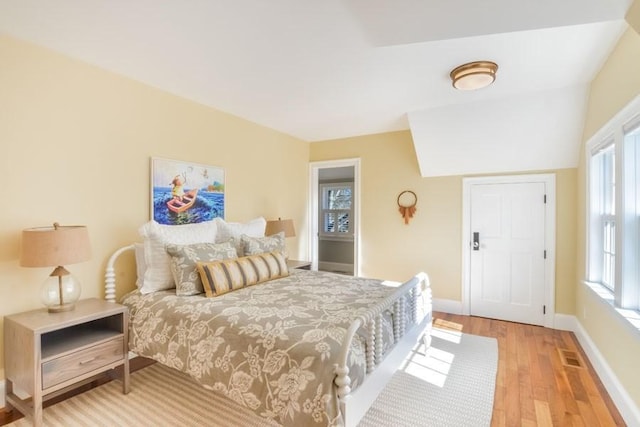 bedroom with light wood finished floors, baseboards, multiple windows, and visible vents