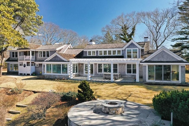 back of house featuring a fire pit, a yard, a pergola, a chimney, and a patio area