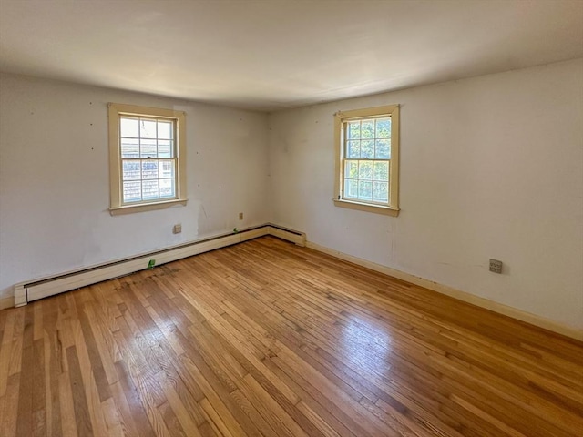 unfurnished room with baseboard heating and light hardwood / wood-style flooring