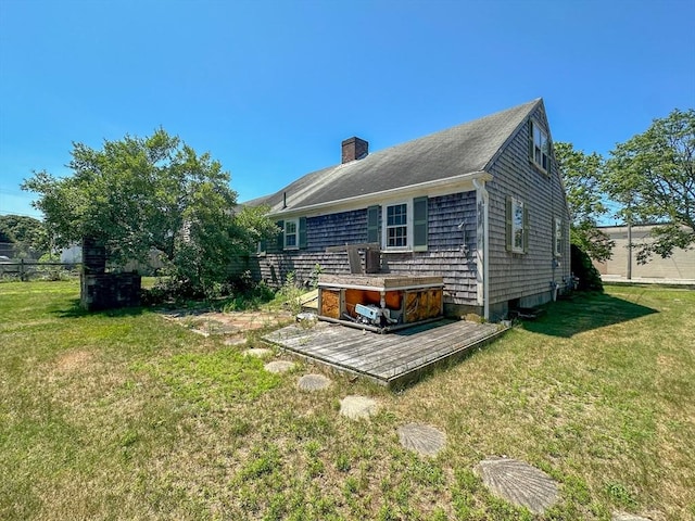 back of property featuring a deck and a lawn