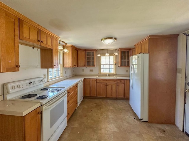 kitchen featuring white appliances, a healthy amount of sunlight, decorative light fixtures, and sink