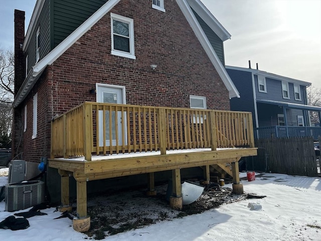 snow covered house with central air condition unit and a deck