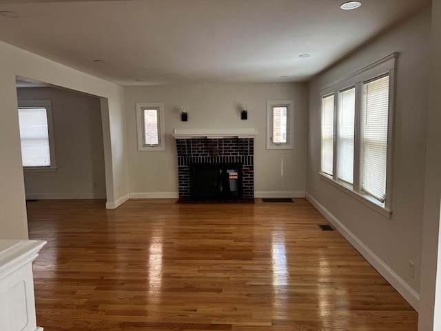 unfurnished living room with dark hardwood / wood-style flooring and a tiled fireplace