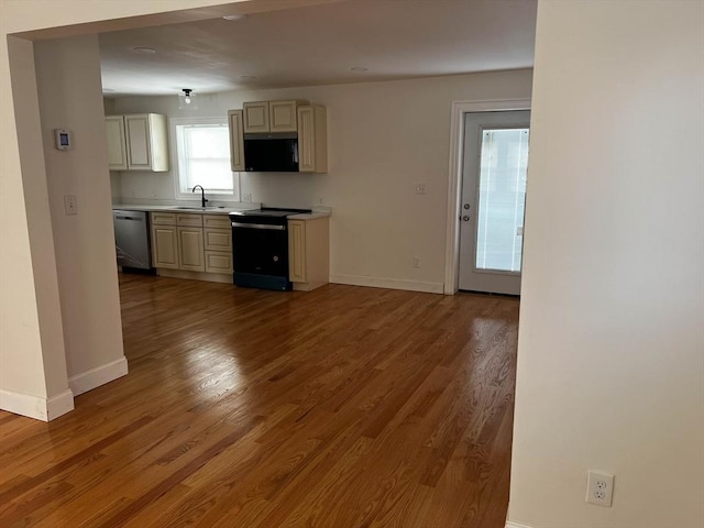 kitchen with black electric range oven, light hardwood / wood-style flooring, stainless steel dishwasher, and sink