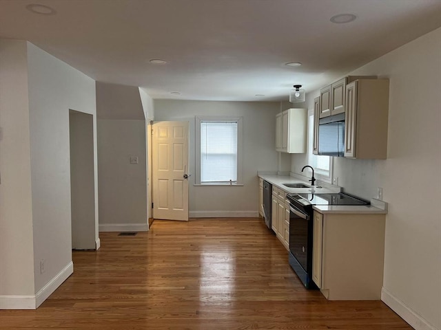 kitchen featuring sink, range with electric cooktop, dishwasher, and light wood-type flooring