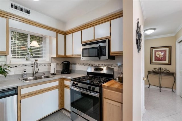 kitchen with stainless steel appliances, a sink, backsplash, ornamental molding, and baseboards