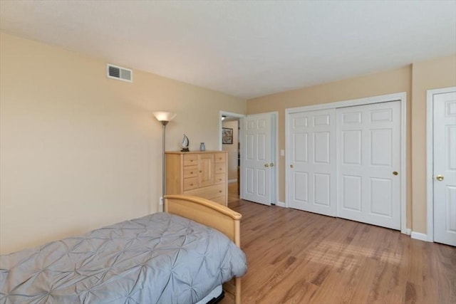 bedroom with light wood finished floors, baseboards, and a closet