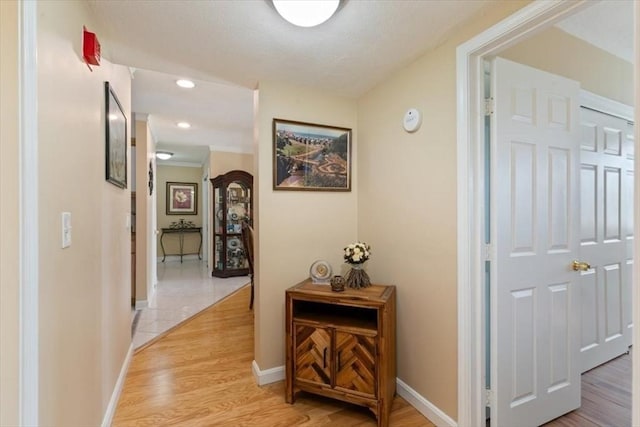 hallway with baseboards, light wood finished floors, and recessed lighting