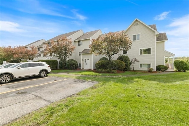 view of front of house with uncovered parking, a front lawn, and a residential view