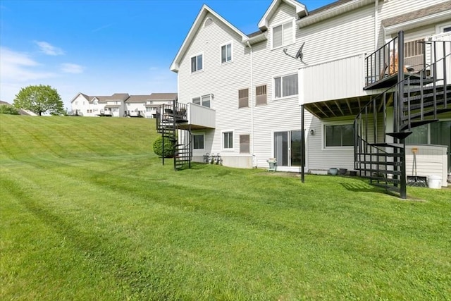 back of property featuring stairway, a wooden deck, and a yard