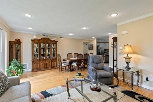 living room featuring crown molding, light wood-style floors, recessed lighting, and baseboards