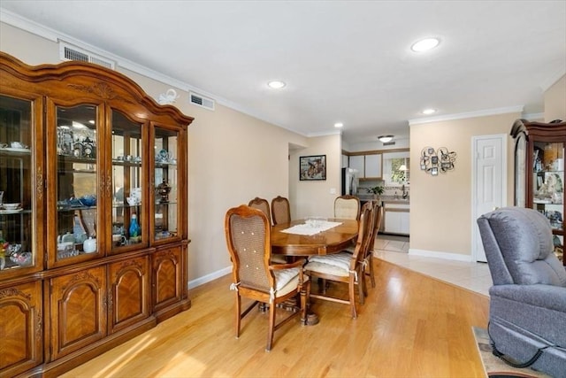 dining space with crown molding, recessed lighting, light wood-style flooring, and baseboards