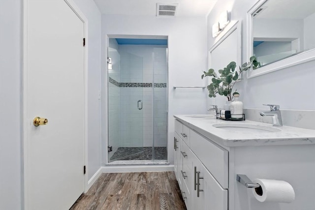 bathroom featuring a stall shower, wood finished floors, and double vanity