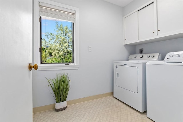 clothes washing area with cabinet space, washing machine and clothes dryer, and baseboards